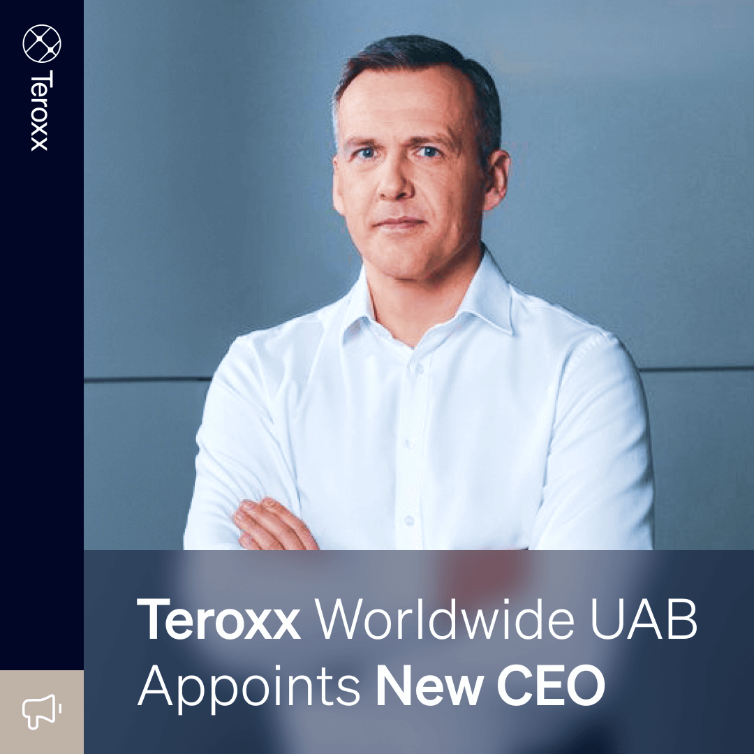 Alenas Gumuliauskas, wearing a white dress shirt, stands confidently with arms crossed against a sleek gray background as CEO of Teroxx Worldwide.